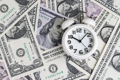 A clock is shown on a field of cash.