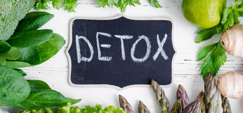 The word Detox on a blackboard, amid healthy looking greens