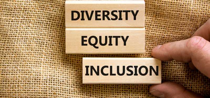 A hand is placing three blocks, labeled Diversity, Equity, and Inclusion.