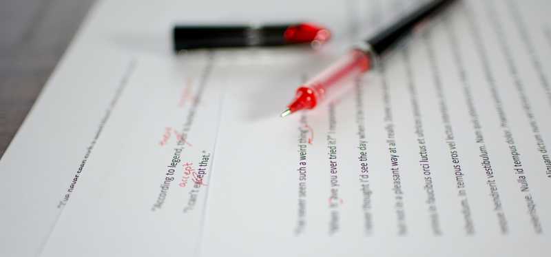Red pen on a manuscript that has been marked up by an editor.