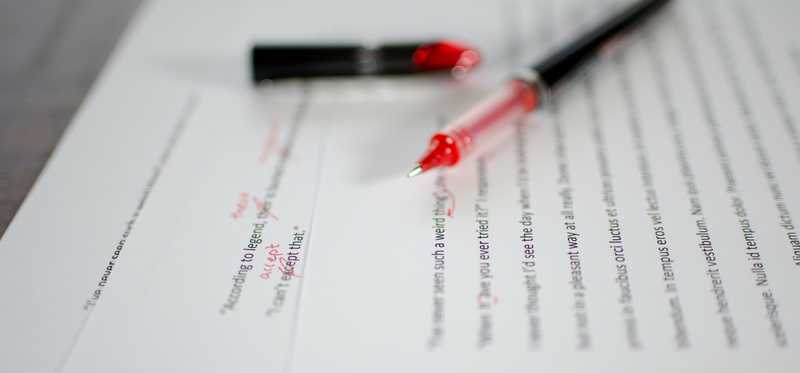 We see a red pen on a manuscript that has been marked up by an editor.