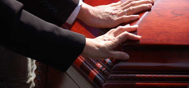 Hands touching a casket.