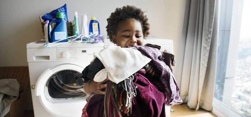 Person happily walking away from a dryer with an armful of laundry.