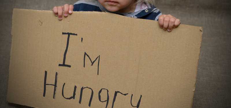 A young girl is holding a sign that says I'm hungry.