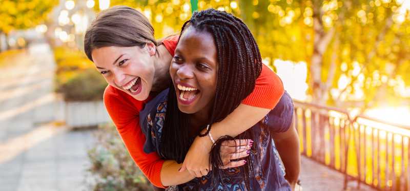 Two people hugging and laughing outdoors.