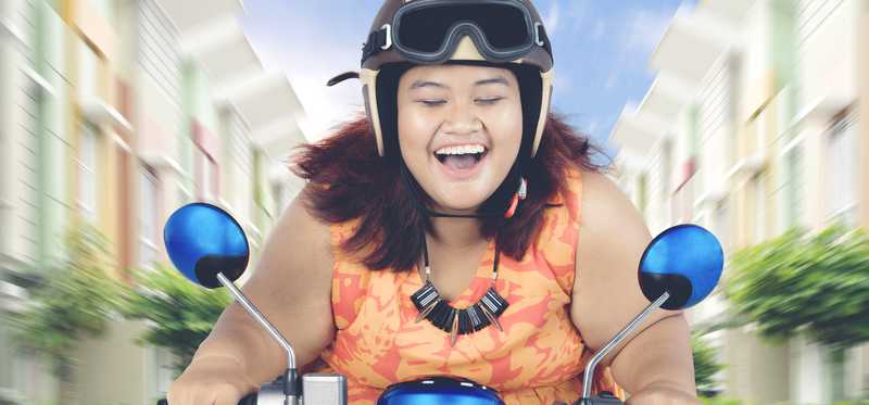 A happy person riding a scooter.