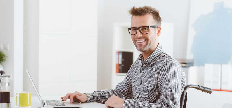 A smiling person sitting at a desk.