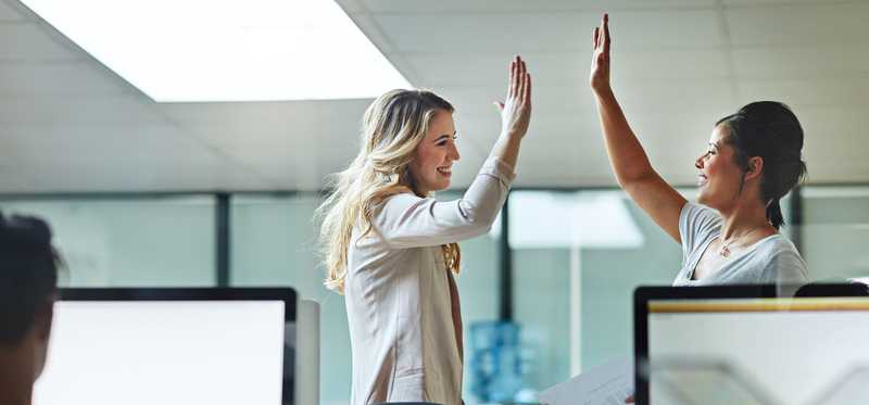 Two happy people are high-fiving each other.