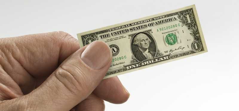 Hand holding a tiny, shrunken dollar bill.