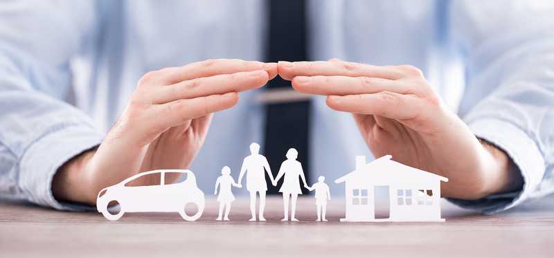 Two hands are hovering over paper cutouts of a home, car, and family.