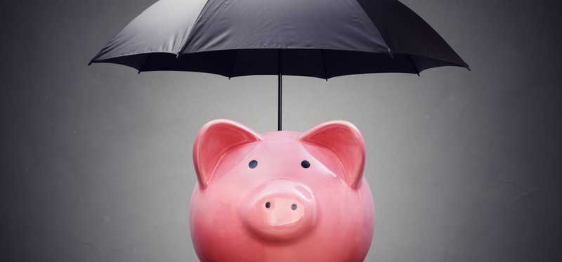 A piggy bank has a black umbrella open above it.