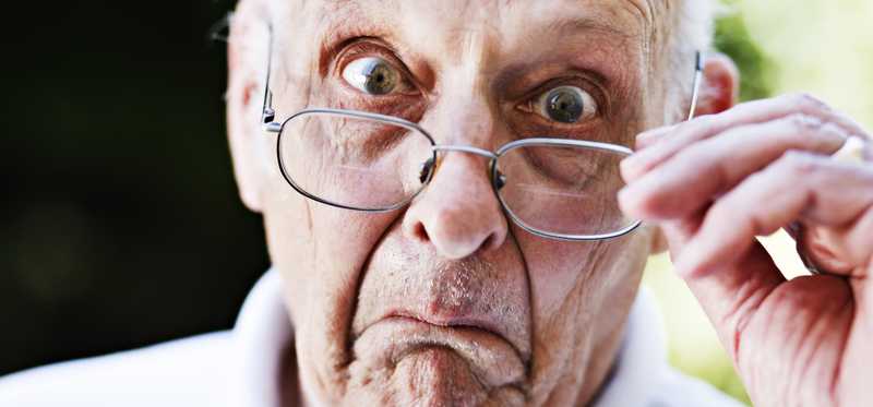 A close-up of a surprised person looking over their glasses.