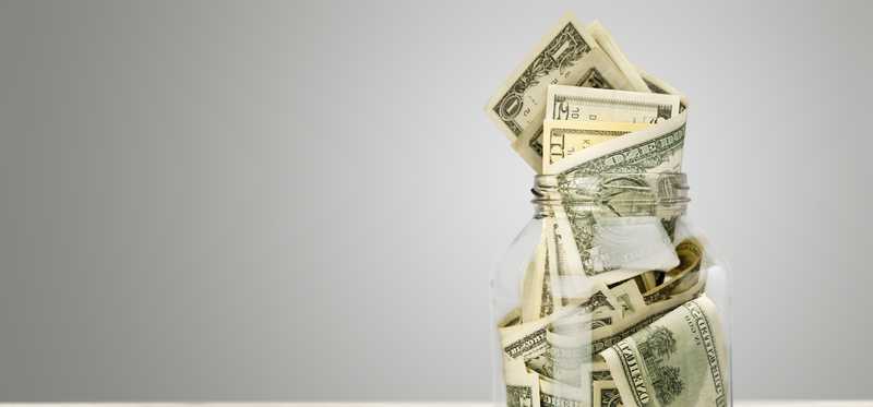 A glass jar stuffed full of cash