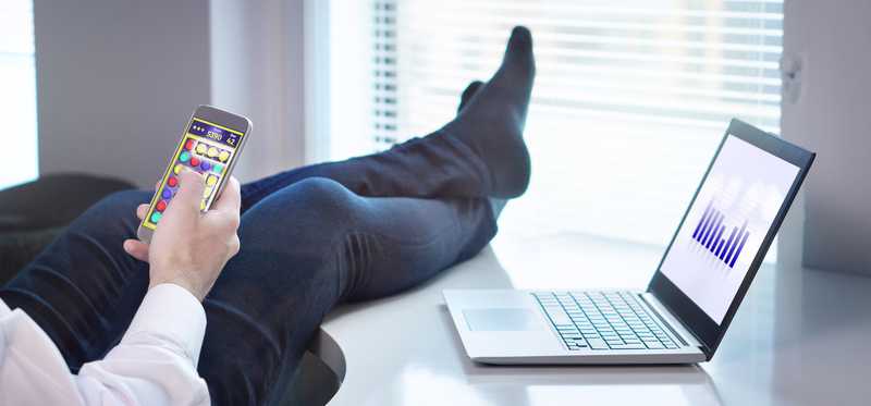 Person with stocking feet up on an office desk while using phone.