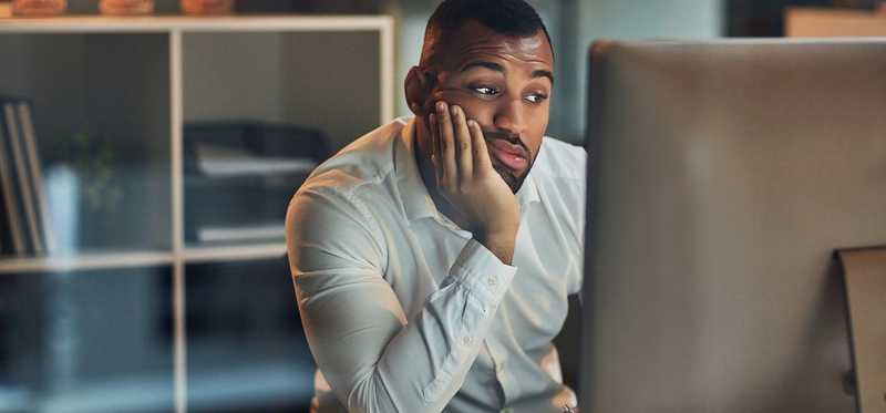 A person sitting at computer and looking bored.