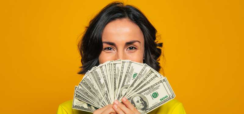 Person peeking out from behind some fanned out cash.