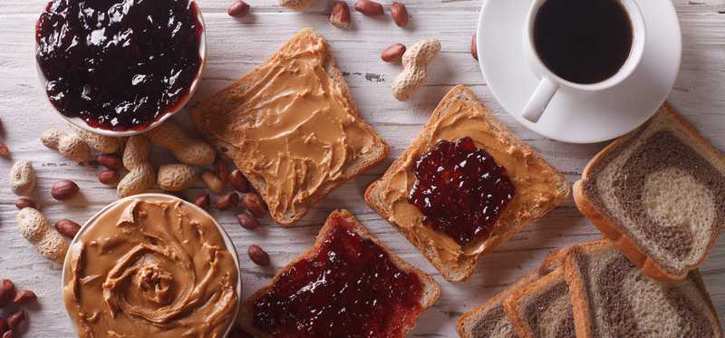 We see an overhead shot of a table with peanut butter, jam, and coffee on it.