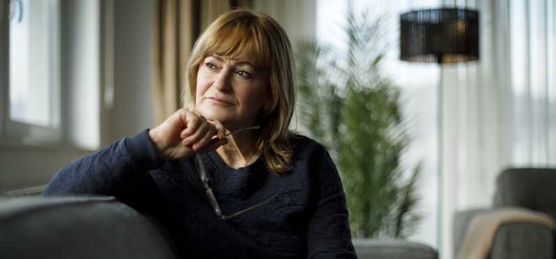Person is seated on a couch, looking away, seemingly deep in thought.