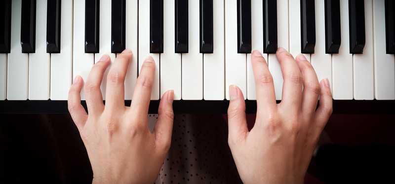 Two hands on a piano keyboard.