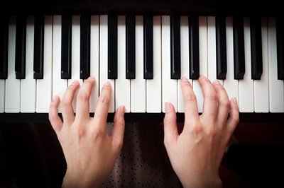 We see two hands above a piano keyboard.