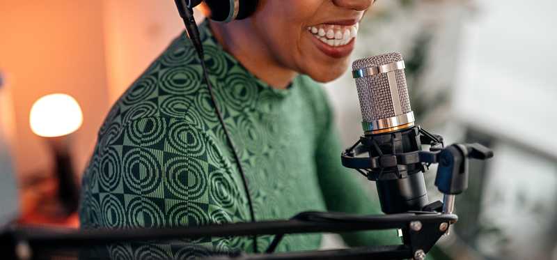 A person smiling and talking into a microphone.