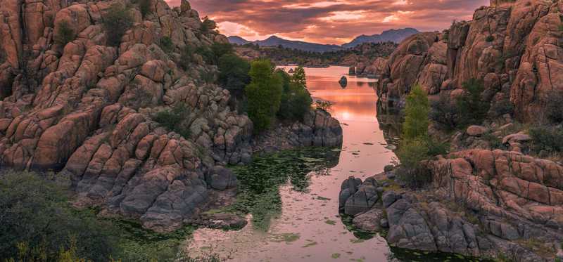 We see desert country by a river at sunset.