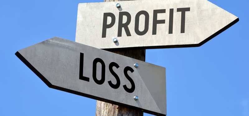 A crossroads sign points in one direction for profit and the other for loss.