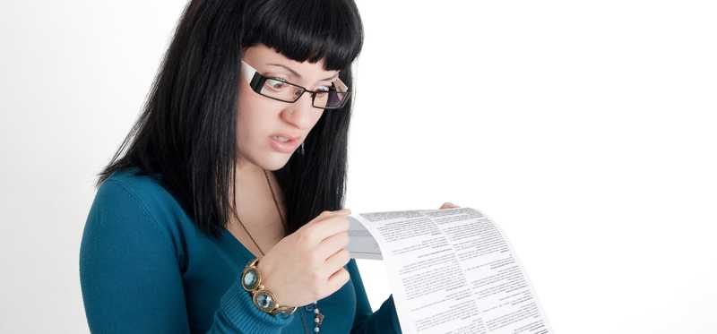 Person is reading a document's fine print and looking surprised.