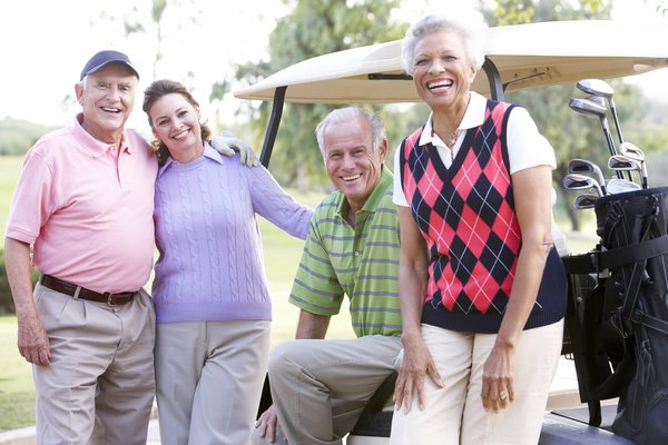 Four people smiling while standing by a golf cart.