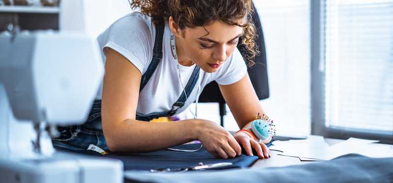 Person sewing next to a sewing machine.