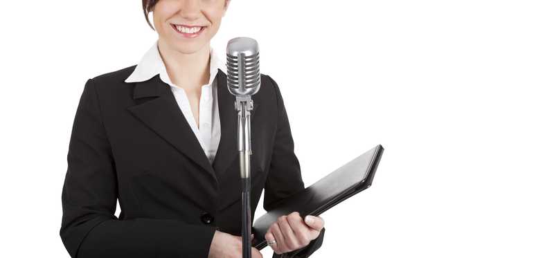 A happy person in a suit is by a microphone.