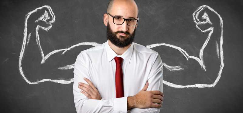 Someone with folded arms is standing in front of a drawing of big biceps.