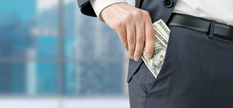 A hand is taking hundred-dollar bills out of a pocket.