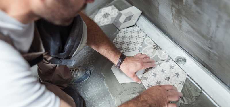 Person tiling a floor in a home bathroom.