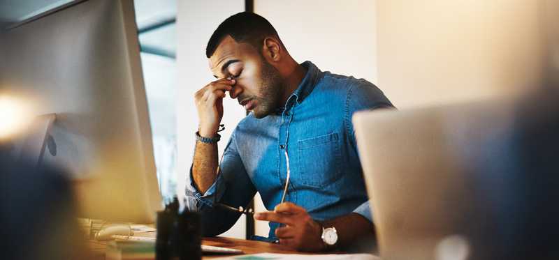 Person rubs eyes while using computer.