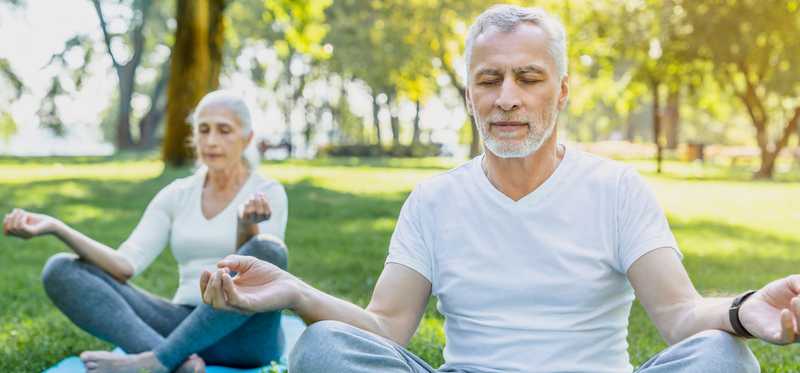Two people are outdoors meditating.