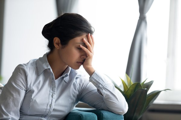 A person looks upset with their head resting in their hand.