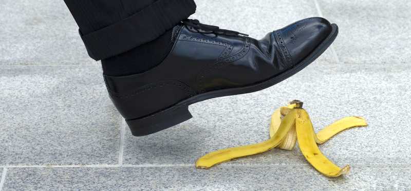 The foot of a person is about to step on a banana peel.