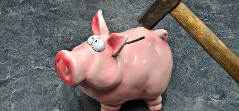 A hammer smashes a piggy bank.