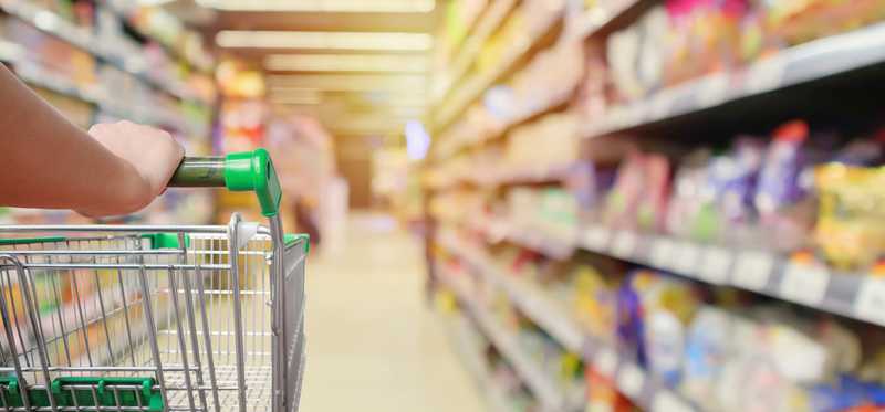 Hand on handle of grocery cart going down aisle