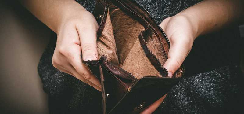 Hands holding empty brown leather wallet.