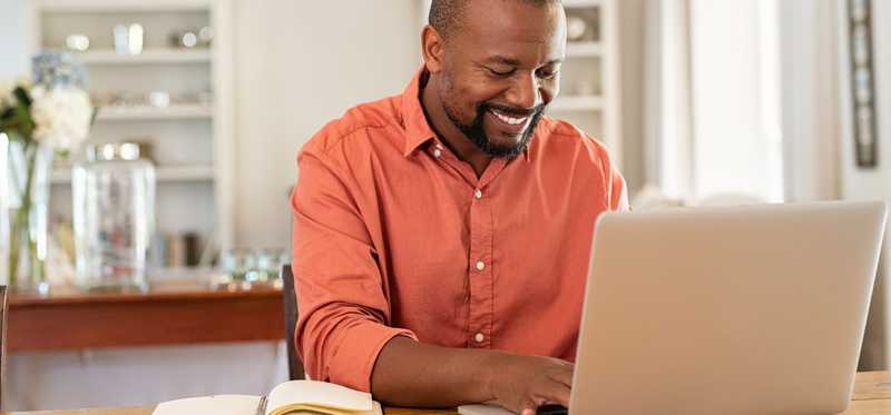 Smiling person typing on laptop.