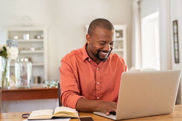 Smiling person typing on a laptop.