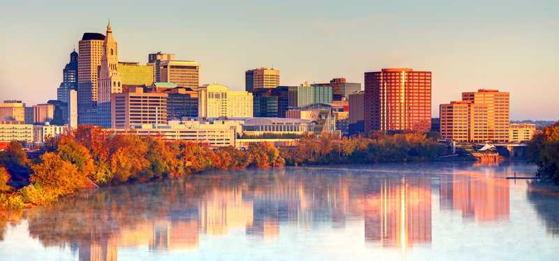 A shot of the fall-colored trees along the bank of the Connecticut River with downtown Hartford in the background.