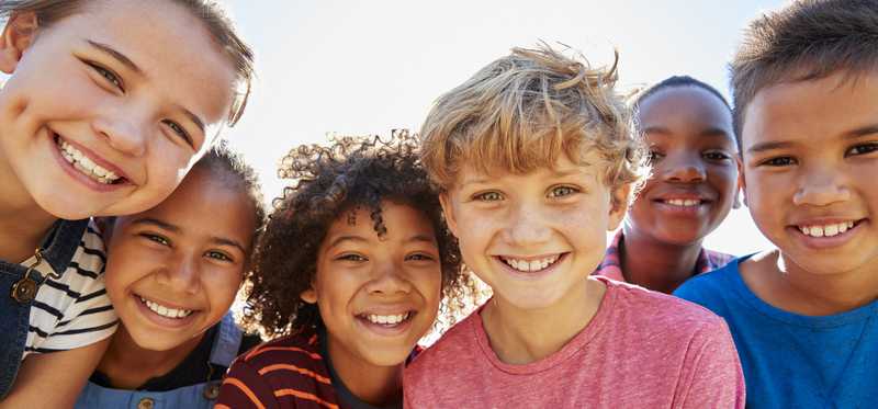 Group of children standing shoulder to shoulder and smiling
