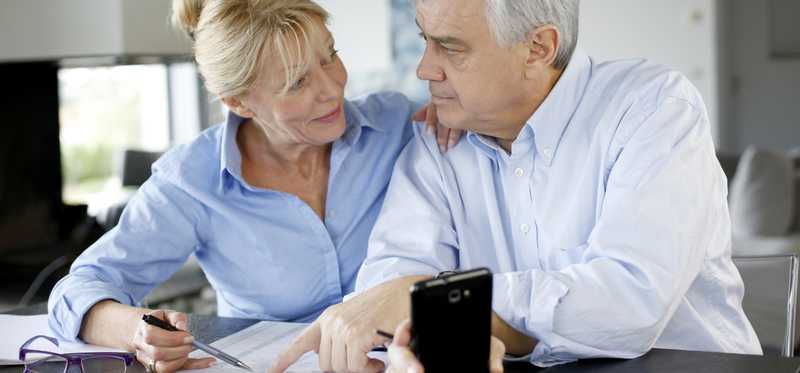 Two people sitting at a table and looking over papers together.