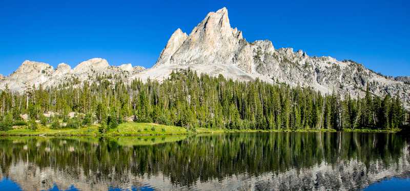 A glass-like body of water reflecting a mountain in the background.