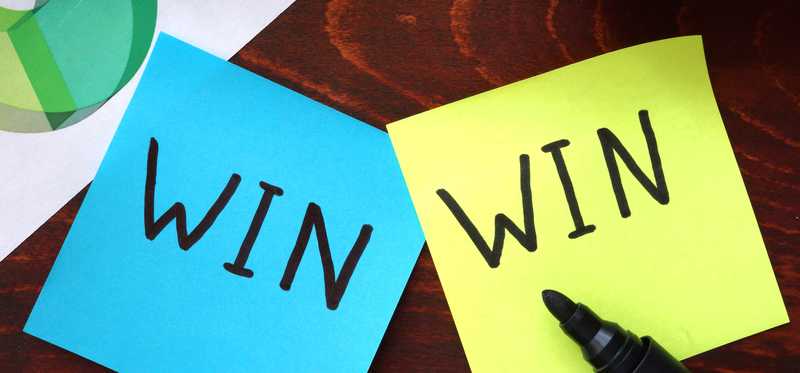 Two different colored Post-it notes both with the word Win on them.