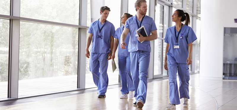 Group of healthcare workers in scrubs walking through a hospital.