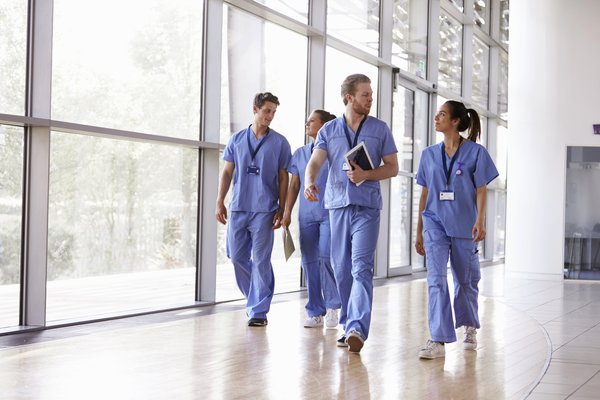 Group of healthcare workers in scrubs walking through a hospital.